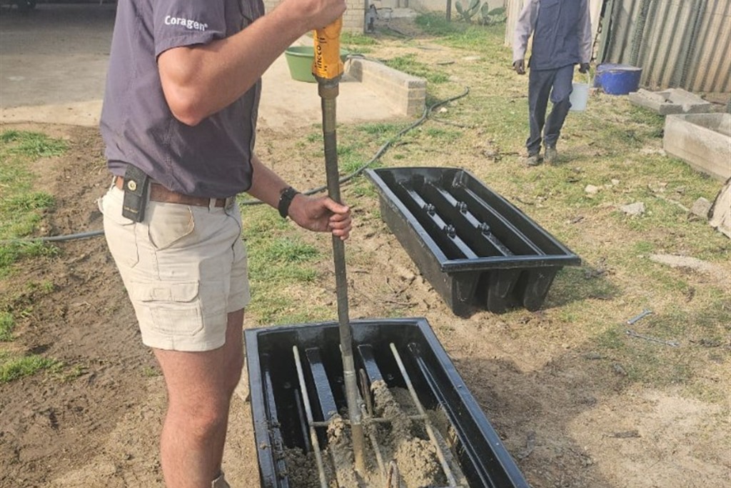 Boer vibreer nat beton in ’n gietvorm met ’n betonvibreerder